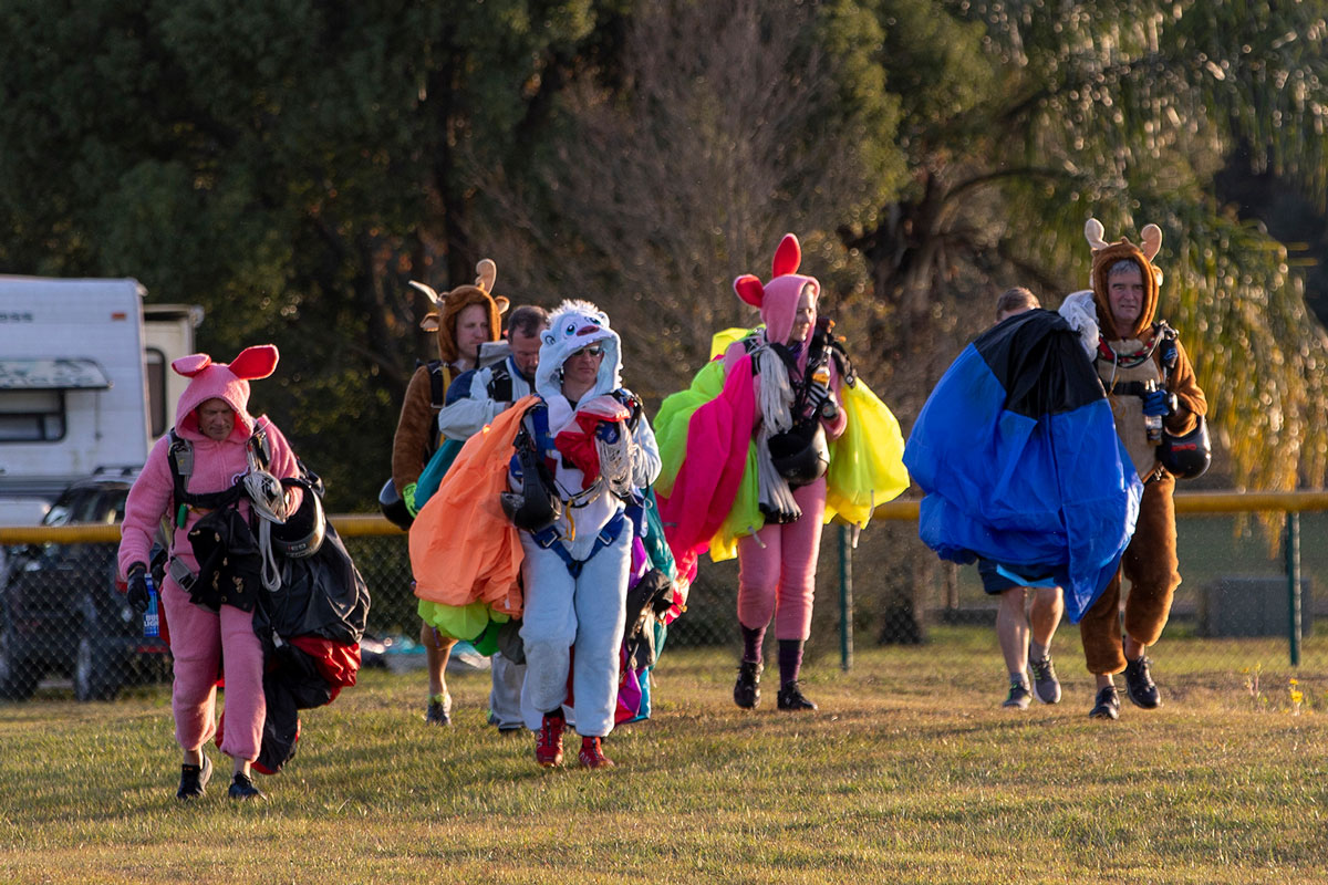 Experienced fun jumpers wearing onesies and holding canopies after skydiving.