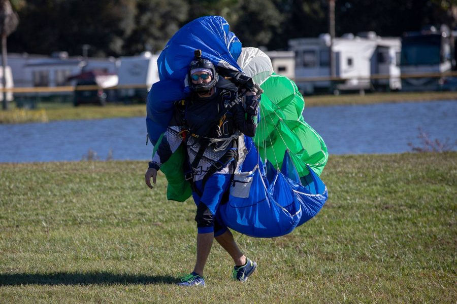 Experienced skydiver holding canopy while walking on grass at Skydive City