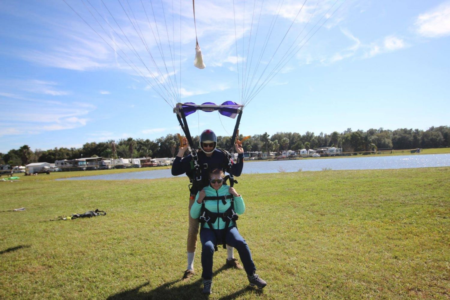 Women landing in grass with tandem instructor after skydiving at Skydive City Z-Hills.