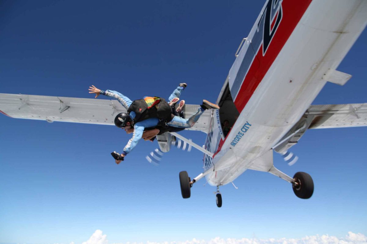 Female skydiver exiting Skydive City airplane with tandem instructor.