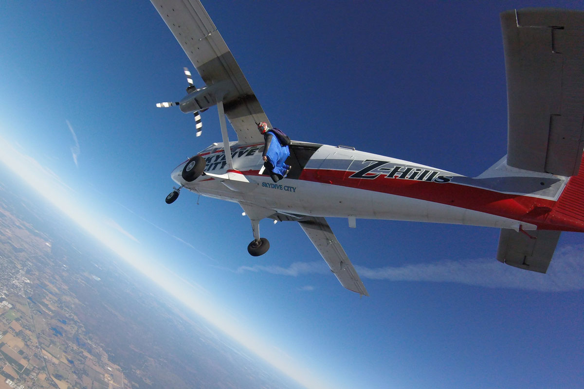 Man in blue wingsuit exiting Skydive City aircraft